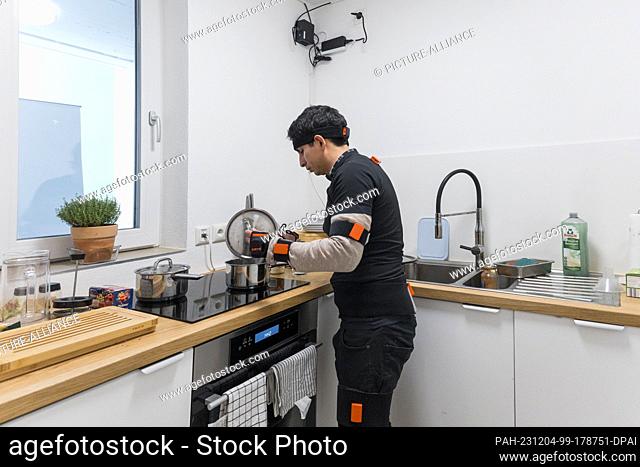 04 December 2023, Bavaria, Kulmbach: ILLUSTRATION - Renato Mio, PhD student, cooks in the kitchen of the Live-In-Lab at the University of Bayreuth (staged...