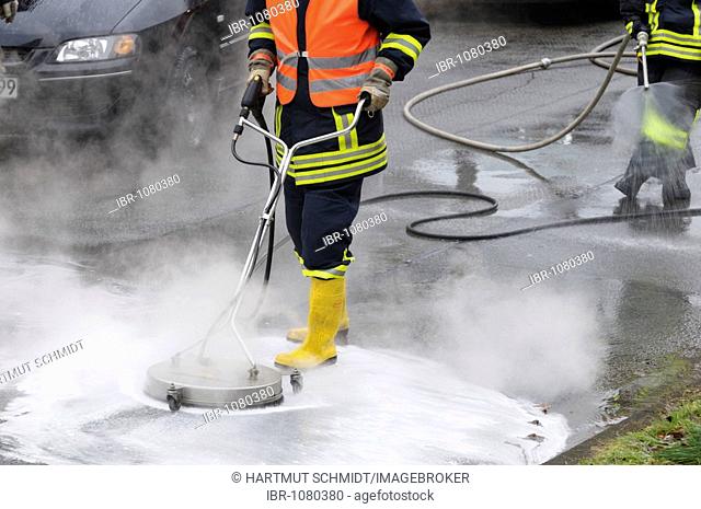 Fire brigade in action, neutralising leaked brake fluid with cleaning equipment and water nozzles