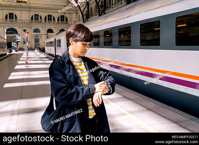 Woman checking time on wristwatch at station