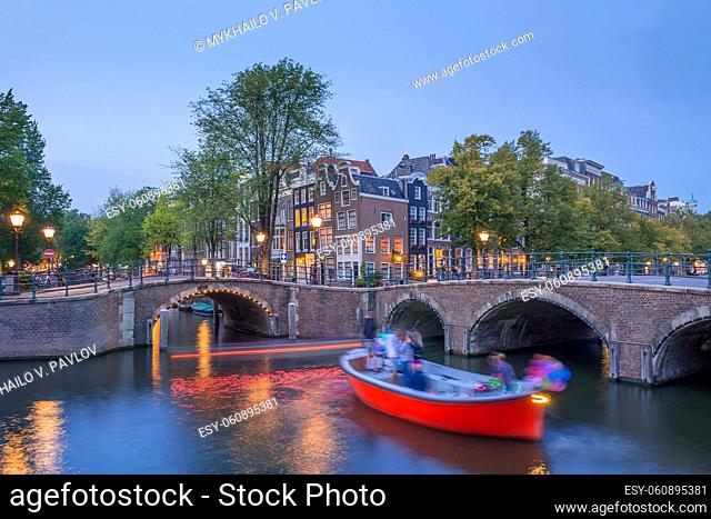 Netherlands. Spring evening on the Amsterdam canal. Street lights and pleasure boat on the water
