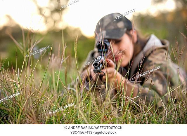 Hunting woman lying on the grass is about to shoot a rifle firearm