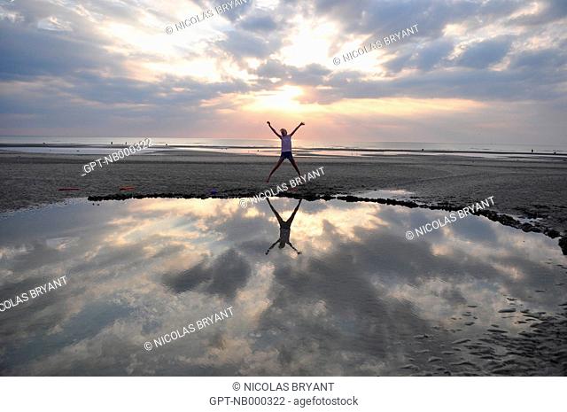 YOUNG GIRL LEAPING ALONG THE BEACH AT SUNSET, CAYEUX-SUR-MER, BAY OF SOMME, SOMME 80, FRANCE