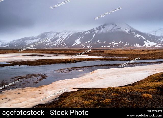 Icelandic landscape with frozen lake, mountains and meadow land covered in snow at snaefellsnes peninsula in Iceland