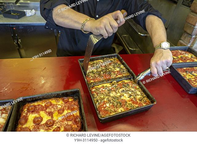 A pizza chef removes a mushroom topped Detroit style deep dish pizza from its pan at the newly opened Lions & Tigers & Squares pizzeria in Chelsea in New York...