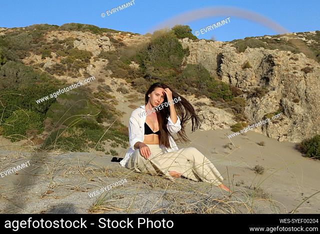 Young woman sitting on sand at beach on sunny day, Patara, Turkiye