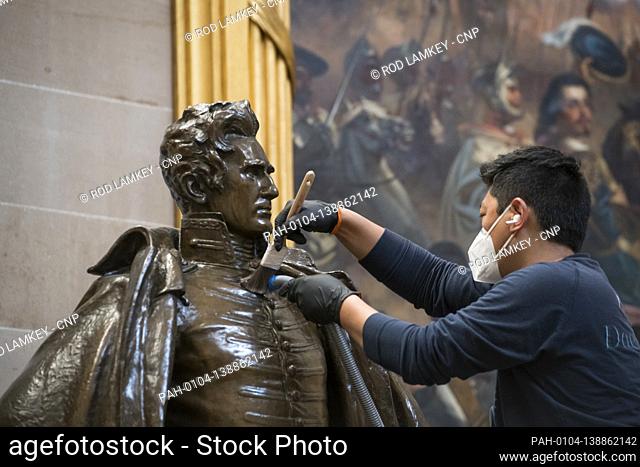 A man works on cleaning up a statue of former President Andrew Jackson in the Rotunda at the U.S. Capitol in Washington, DC, Tuesday, January 12, 2021