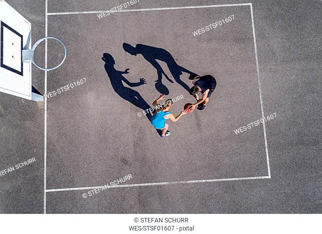 Young man and woman playing basketball, aerial view