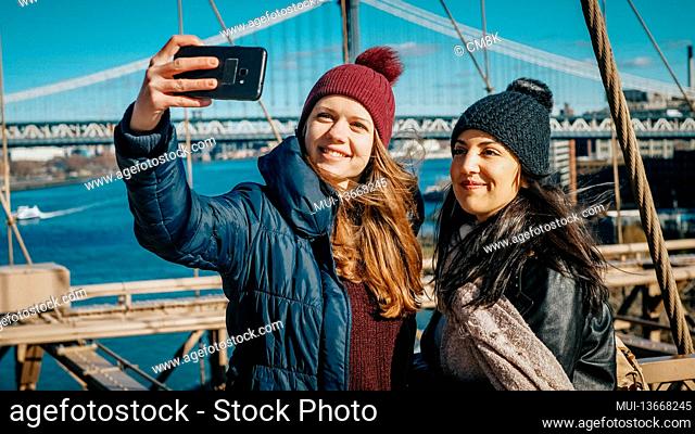 Two friends in New York walk over the famous Brooklyn Bridge - travel photography