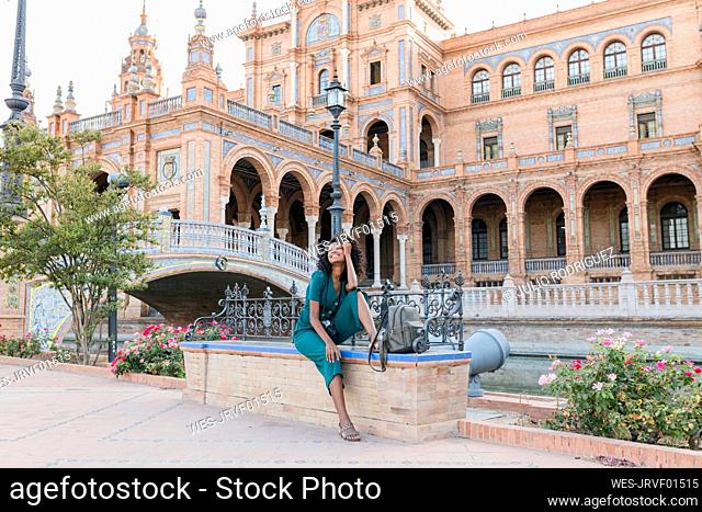Happy female tourist sitting on bench at Plaza De Espana, Seville, Spain