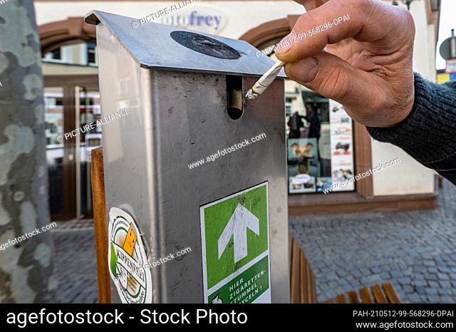 27 April 2021, Bavaria, Amberg: A smoker throws a cigarette butt into a collection container. For three years, the association ""Amberger Kippenjäger"" has been...
