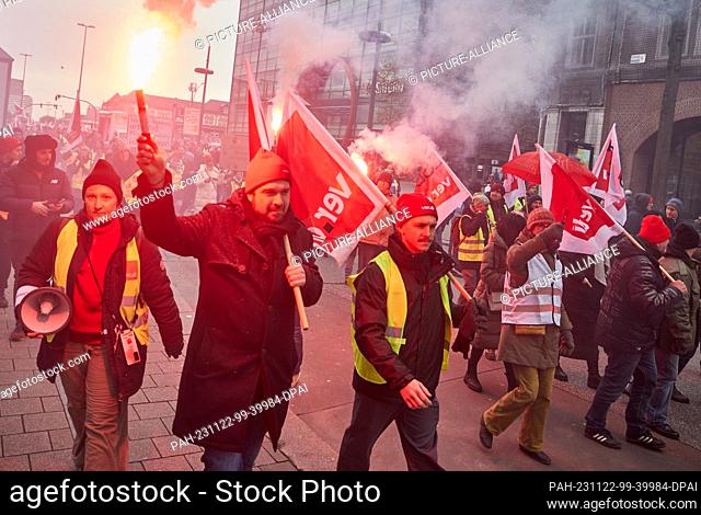 22 November 2023, Hamburg: Participants at a rally on Mönckebergstraße hold flags with the words ""ver.di"" and Bengal flares