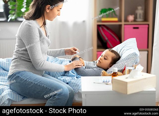 mother measuring temperature of sick daughter