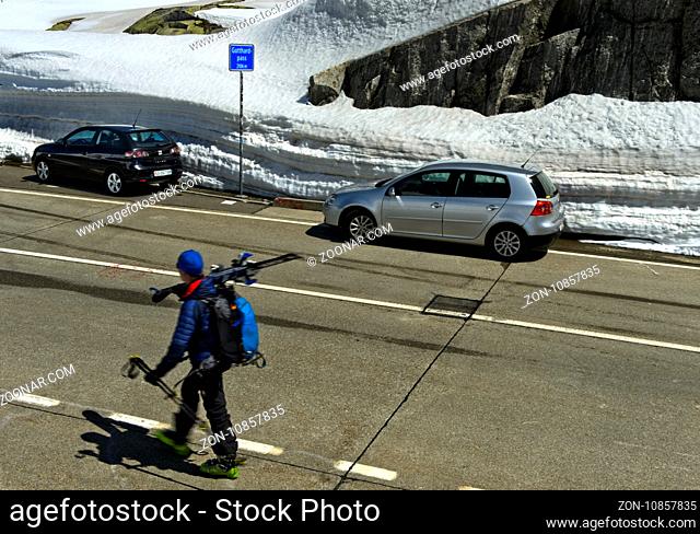 Fussgänger mit Ski und Autos auf der Passhöhe, Gotthardpass, Airolo, Kanton Tessin, Schweiz / Pedestrian with skis and cars at the highest point of the St...