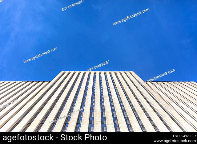 Brutalist skyscraper with deep blue skies looking up. Copy space in the sky with nondescript building occupying the foreground
