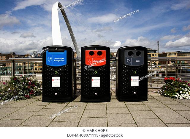 England, Tyne and Wear, Gateshead. Recycling bins on the quayside in Gateshead with the Gateshead Millennium Bridge in the background