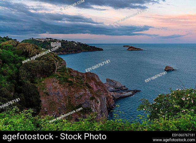 Evening light over Daddyhole Cove, with a view over the cliffs, the sea and Thatcher's Rock in Torquay, Torbay, England, UK