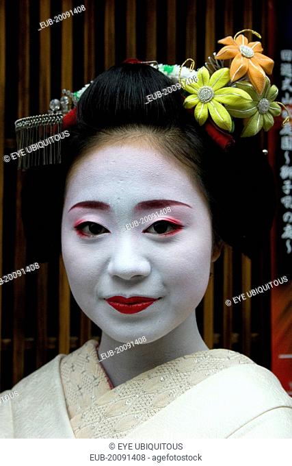 Gion District. Head and shoulders portrait of smiling Maiko or apprentice Geisha, with hair worn up and fixed with decorative pins and flower ornaments