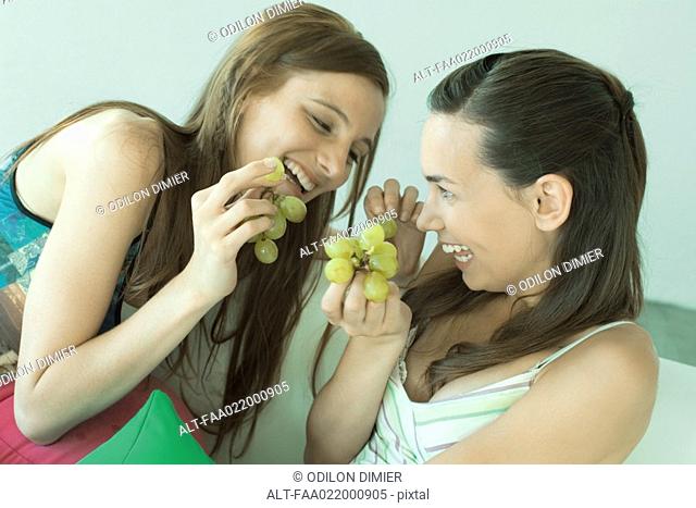 Two young friends eating grapes, laughing