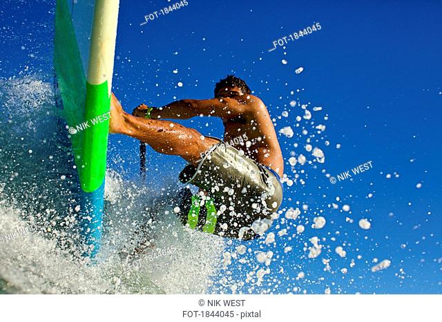 Young man riding paddleboard on ocean wave