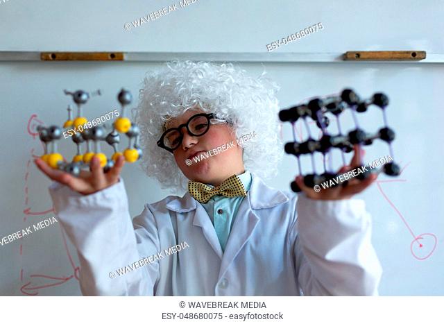 Schoolboy in white wig holding molecule model in laboratory