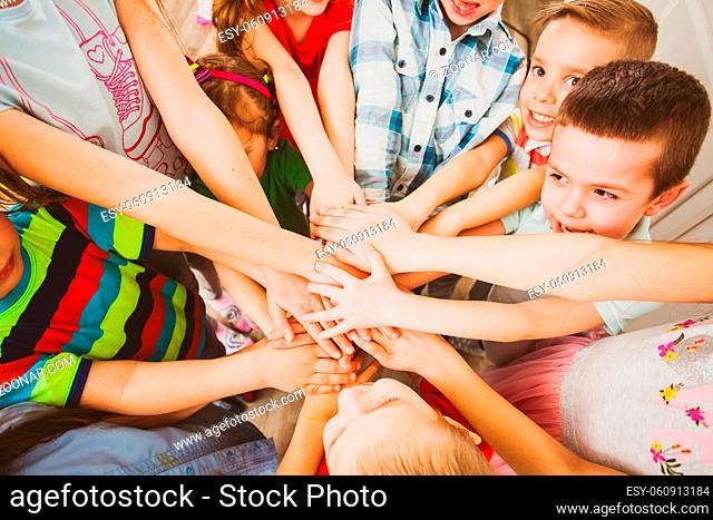 Little children putting their hands together outdoors. Unity, team work, friendship concept