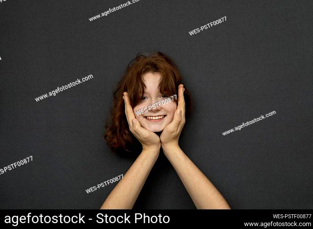 Studio shot of head of teenage girl leaning on male hands