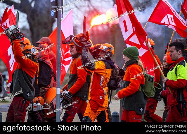 28 November 2023, Mecklenburg-Western Pomerania, Schwerin: Forestry workers with chainsaws take part in a protest action in the ongoing wage dispute in the...