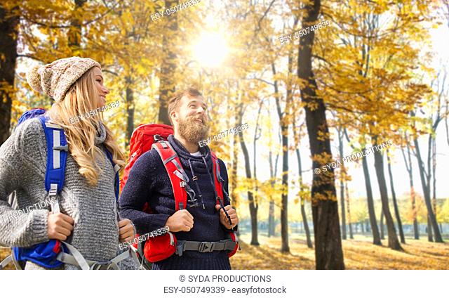 smiling couple with backpacks hiking in autumn