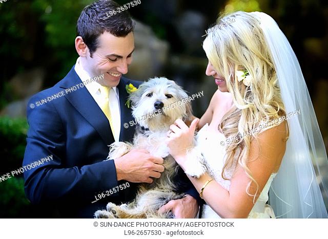 happy bride & groom petting dog on wedding day