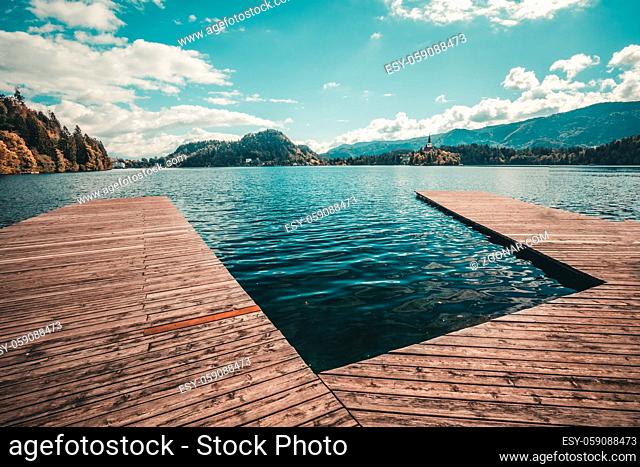 Wooden pier on the Bled lake in Slovenia with famous island and castle on background