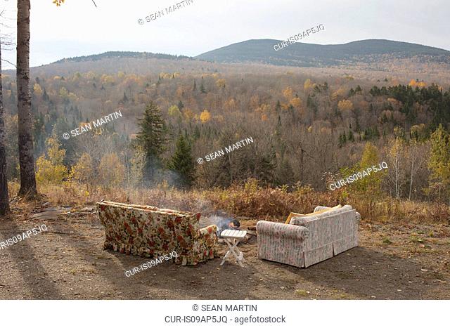 Two sofas and campfire with autumn forest view, Maine, USA