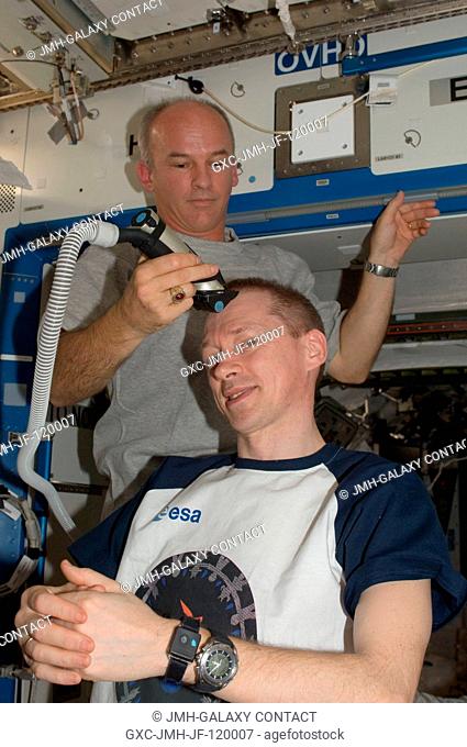 NASA astronaut Jeffrey Williams, Expedition 21 flight engineer, trims European Space Agency astronaut Frank De Winne's hair in the Destiny laboratory of the...