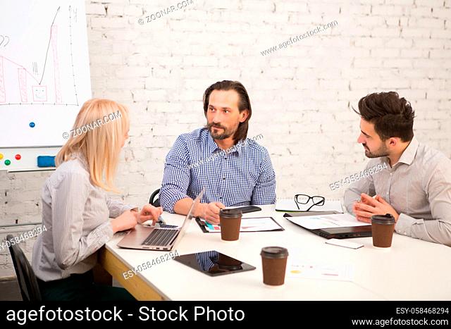 Picture of businesspeople working at table in iffice and discussing difficult business issues connected with companies, firms and enterprises