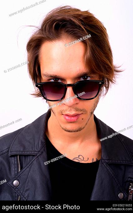 Studio shot of young handsome rebellious man wearing stylish clothes against white background