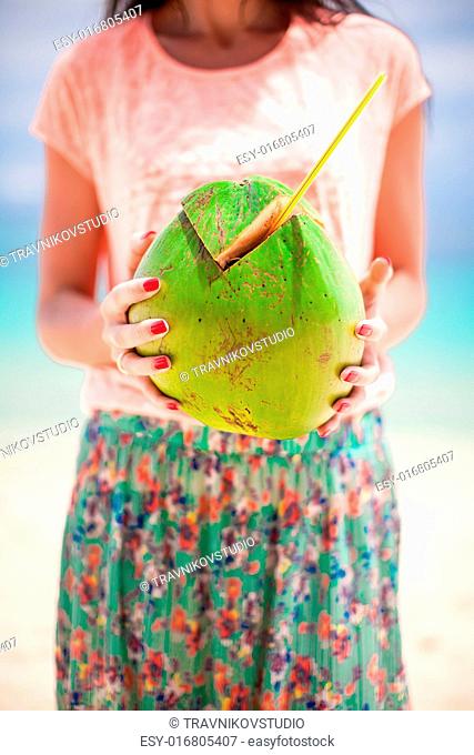 Closeup green big coconut in hands of young woman