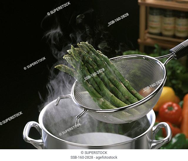 Boiled asparagus being strained on a sieve