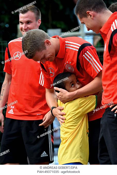 Matthias Ginter (C) of the German national team hugs a school child during their visit to the primary school in Santo Andre, Brazil, 11 June 2014