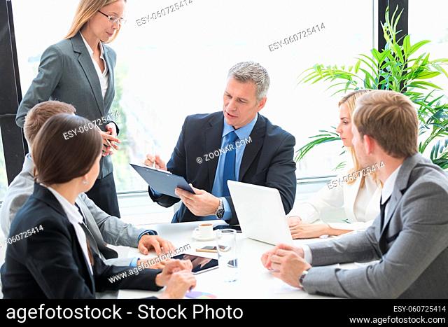 Mixed group of white collar workers at business meeting discuss documents, Business man reading contract at office table