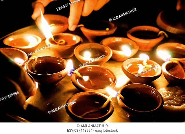 Hands lighting and picking up earthenware diwali lamps