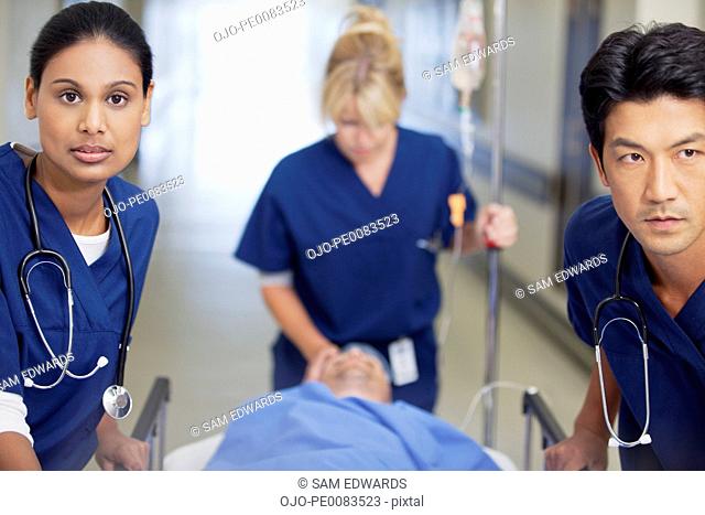Nurses wheeling patient on gurney down hospital corridor