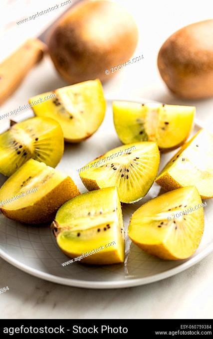 Halved ripe yellow kiwi fruit on plate