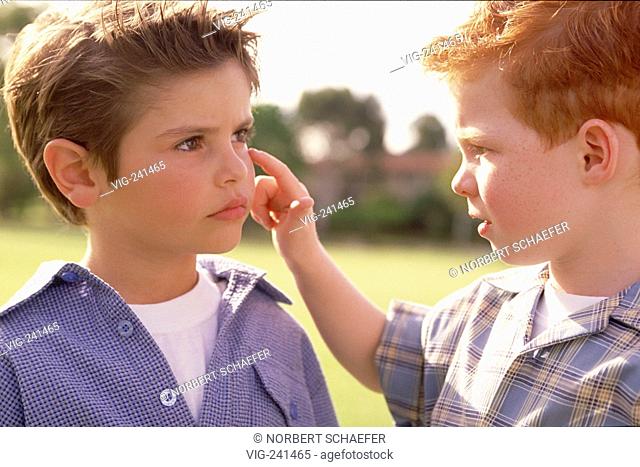park-scene, portrait, close-up, 6 years old redheaded boy with freckles looks at the eye of his friend in the same age, both wearing checked shirts  - GERMANY