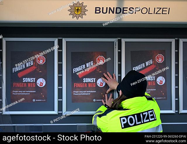 20 December 2023, Saxony, Bärenstein: A federal policewoman puts up posters with the words ""Hands off, otherwise hands off"" on how to handle fireworks