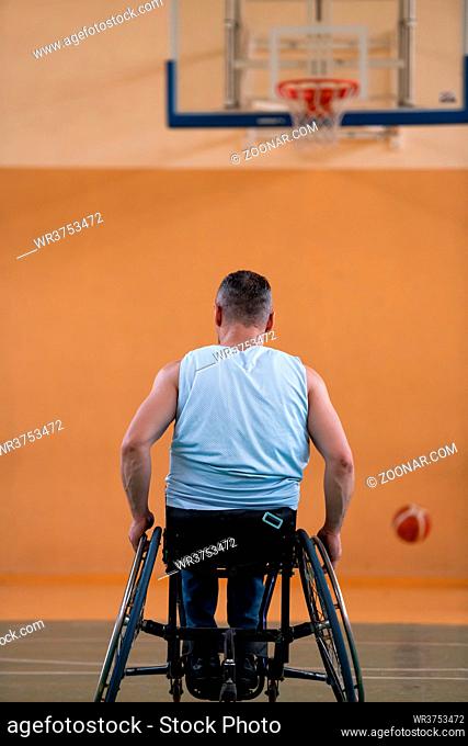 a war invalid in a wheelchair train with a ball at a basketball club in training with professional sports equipment for the disabled