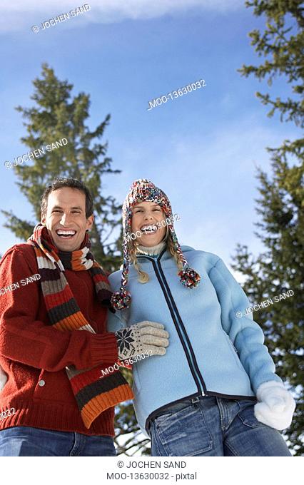 Couple wearing winter clothing standing on hillside low angle view portrait