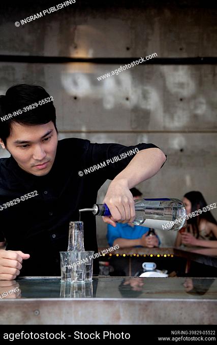 Bartender pouring liqueur on shot glass pyramid