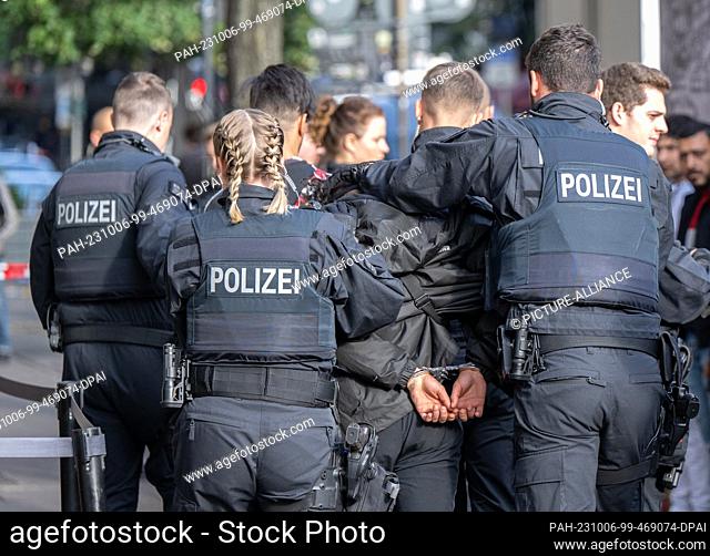 06 October 2023, Hesse, Frankfurt/Main: Officers of a police unit take away a suspect in the station district of Frankfurt am Main
