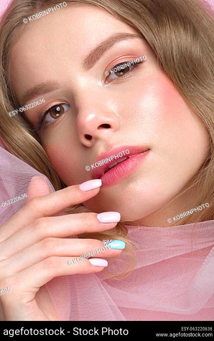 Beautiful girl with light make-up and gentle manicure in pink clothes. Beauty face. Design nails. Photo taken in studio on pink background