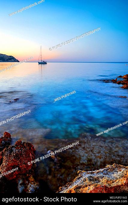 Spain, Balearic Islands, Lone yacht near shore of Cala Agulla at dusk