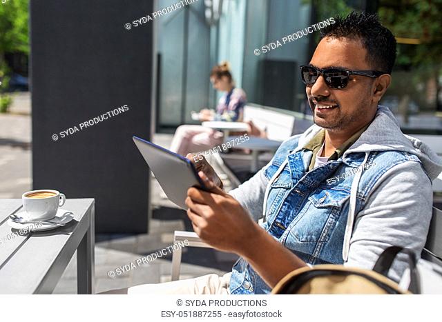 man with tablet pc and coffee at street cafe